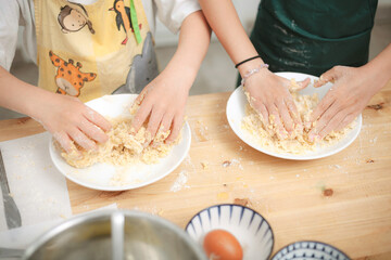 Siblings kneading cookie dough together in family kitchen
