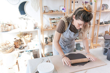 Ceramist working with a roller in a studio with natural light.