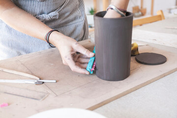 Fototapeta na wymiar Woman potter applying a decorative motif to a ceramic piece.