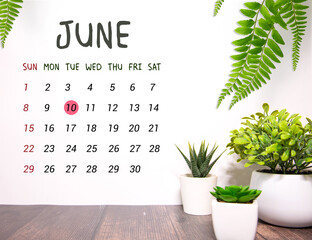 Wooden block calendar with date June 10 on pink concrete background.