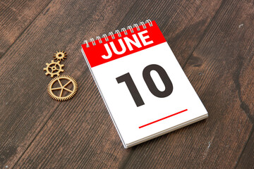 Wooden block calendar with date June 10 on pink concrete background.