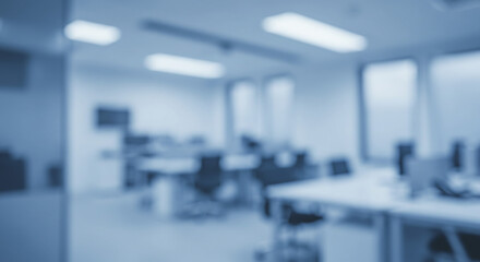 A blurred view of a modern office space with desks chairs and computers in blue monochrome tones