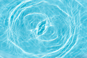 Blue water with ripples on the surface. Defocus blurred transparent blue colored clear calm water surface texture with splashes and bubbles. Water waves with shining pattern texture background.