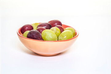 Close-up of fresh grapes in a small bowl, on a white background.
