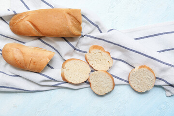 Cut fresh baguette on light blue background