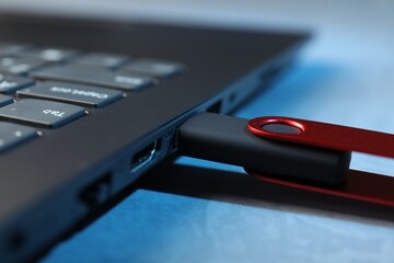 Usb flash drive connected to laptop on blue table, closeup