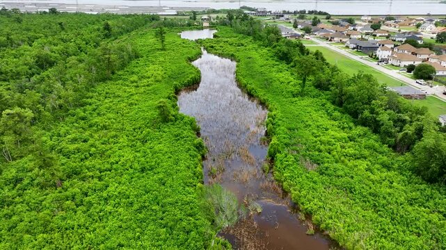 aerial footage of homes and marshland with water and lush green trees in Chalmette Louisiana USA