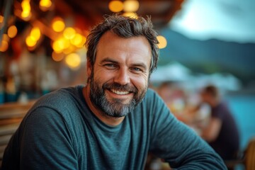 Obraz premium Relaxed man with a beard smiling outdoors at a cafe.