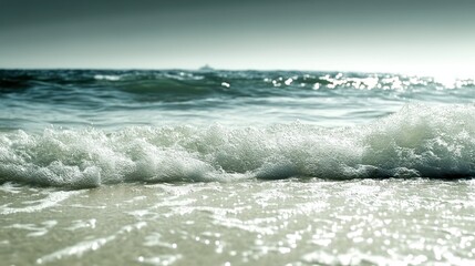 Fototapeta premium Waves crashing onto the sand on a sunny and bright day