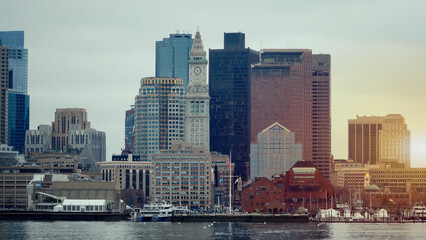 Fototapeta premium Boston skyline with its Custom House Tower reflecting on the water at sunset, as seen from the Long Wharf