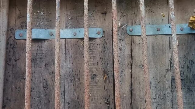 A weathered, rustic wooden door with a metal grill, exuding an atmosphere of aged antiquity and fortitude. revealing the passage of time and strength through its time-worn details.