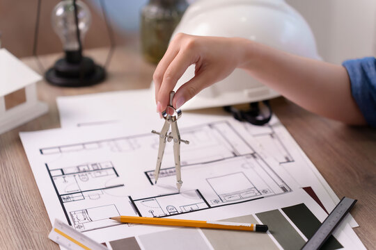 Architectural Design: Woman's Hand Using Compass on Blueprint for House Renovation Project and Real Estate Planning for Ideal Home Architectural Design - Powered by Adobe