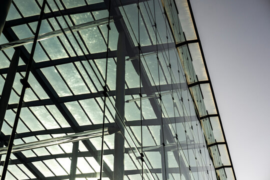 Angled view of contemporary building with translucent glass panels and visible interior grid, exploring light, transparency and geometric composition.