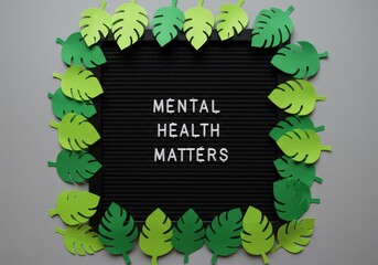 A motivational message board with the phrase "mental health matters" is surrounded by leaves.