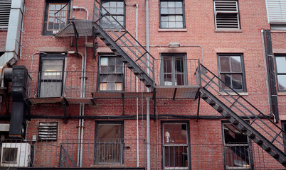Metal fire escape zigzagging across red brick wall with windows and balconies in Boston, Massachusetts