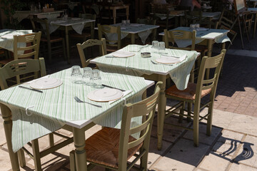 Outdoor Taverna Table Setting. Traditional Greek taverna table set with plates and glassware, shaded and ready for guests in Zakynthos, Greece.