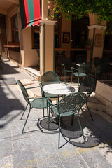 Cafe Table in Narrow Greek Alley. Metal cafe table and chairs sit in the shade of a quiet alleyway in Zakynthos, Greece.
