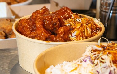Deep-fried boneless Korean chicken pieces with spicy sauces and mayo on a white rice bowl. Crispy outside, juicy and succulent inside, smelling delicious.