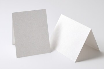 Two blank cards, one light gray and one white, sit on a white surface. Perfect for your message!