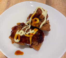A stack of deep-fried boneless chicken pieces with spicy sauces and mayo. Crispy outside, juicy and succulent inside, smelling delicious.