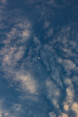 Crescent moon and clouds in the blue sky at sunset time.