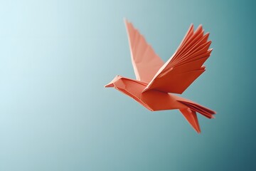 Obraz premium Orange origami bird soaring against a beautiful light blue gradient sky showing freedom