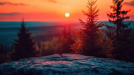 Majestic sunset over a mountain peak.  Rocky outcrop foreground, pine trees in the background