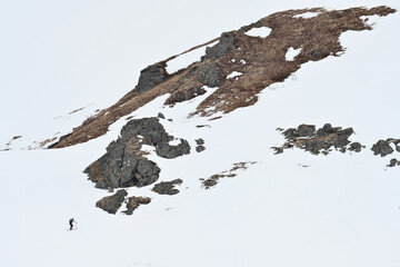 A backcountry skier makes his way up a steep, rugged Alaska mountain for some late-season skiing.