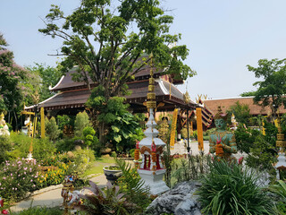 A peaceful Buddhist temple garden with statues, greenery, stupas, and traditional architecture...