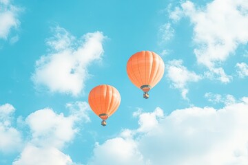 Fototapeta premium Two orange hot air balloons float peacefully in a vibrant sky filled with fluffy white clouds