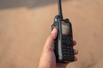 A radio operator is holding a rugged Walkie-Talkie, close-up and selective focus.