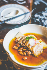 BRAISED DUCK with tofu slices and braised peanuts in a white dish