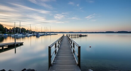 Obraz premium Wooden Pier Extending Into Calm Lake at Sunset with Boats