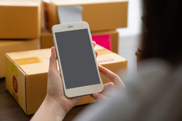 Hand holding smartphone with a blank screen on table, for putting advertising to promote.