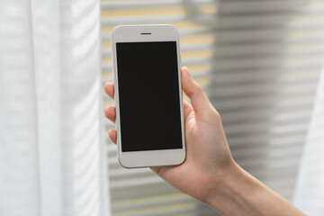 Hand holding smartphone with a blank screen on table, for putting advertising to promote.
