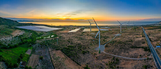 Tall windmill turbines against a clear blue sky, generating renewable energy in the serene Ninh...