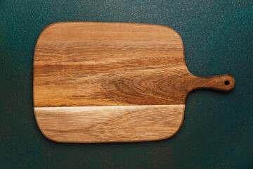 Wooden cutting board displayed on a textured green surface with natural grains