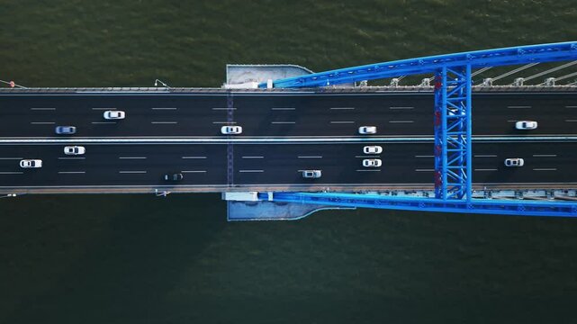 Top down view of highway traffic flows in both directions on a wide bridge spanning a river. Hangzhou, China.