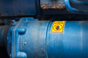 Hand and finger injury caution sign in yellow placard is placed on the machinery part. Safety sign...