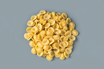 Top view of isolated a raw Italian durum wheat orecchiette pasta on a grey background , place for...