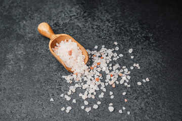 Wooden scoop with pink himalayan salt on dark background