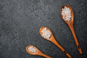 Set of wooden spoons with pink himalayan salt on black background