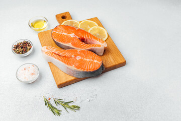 Fresh salmon fillets ready for cooking with lemon and spices on a wooden board