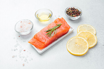 Fresh salmon fillet with herbs, lemon slices, and spices ready for preparation