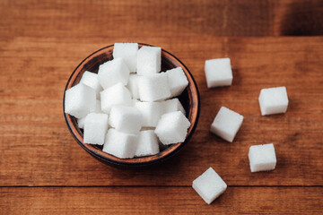 Sweet sugar cubes in a rustic bowl on a wooden table