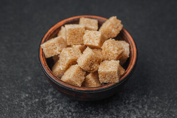 Brown sugar cubes arranged neatly in a decorative bowl on a dark countertop