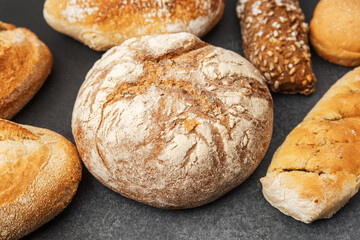 Variety of fresh bread loaves arranged on a dark surface for display