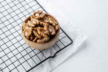 Walnuts in a wooden bowl on a cooling rack with white background