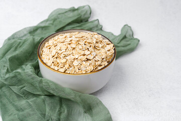 Oatmeal preparation with rolled oats in a bowl on a light background