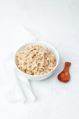 Healthy oatmeal bowl with a wooden spoon on a light background
